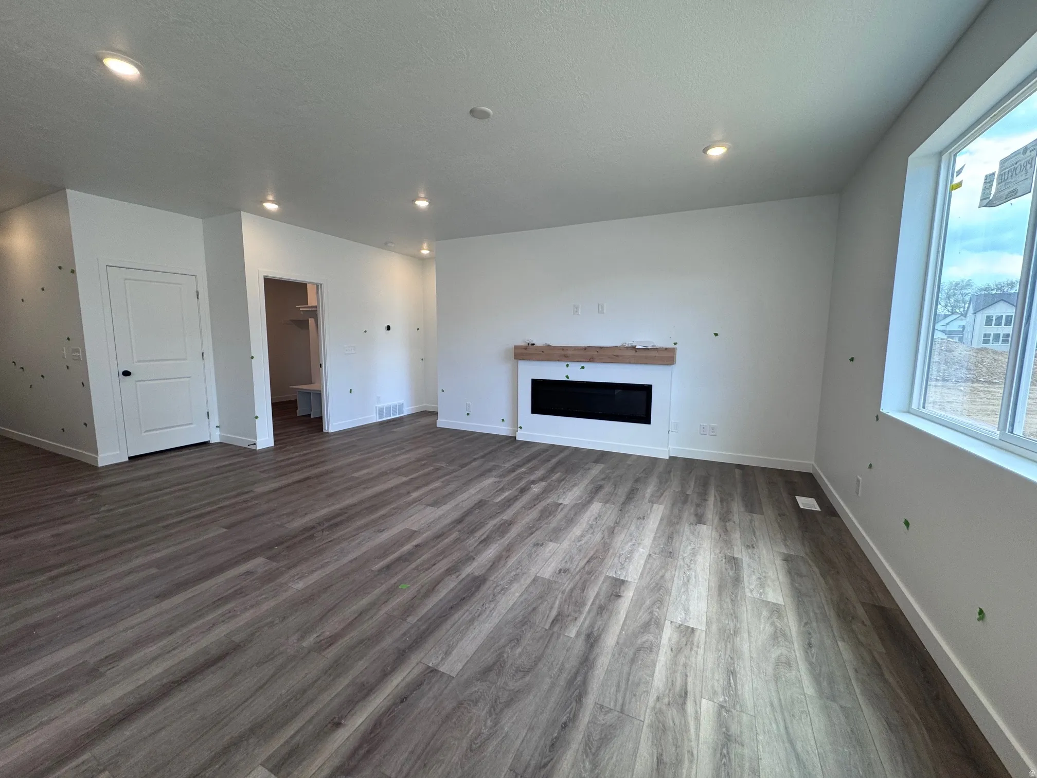 Spacious living area featuring wood-finish flooring, recessed lighting, and an integrated electric fireplace with a floating wood mantel