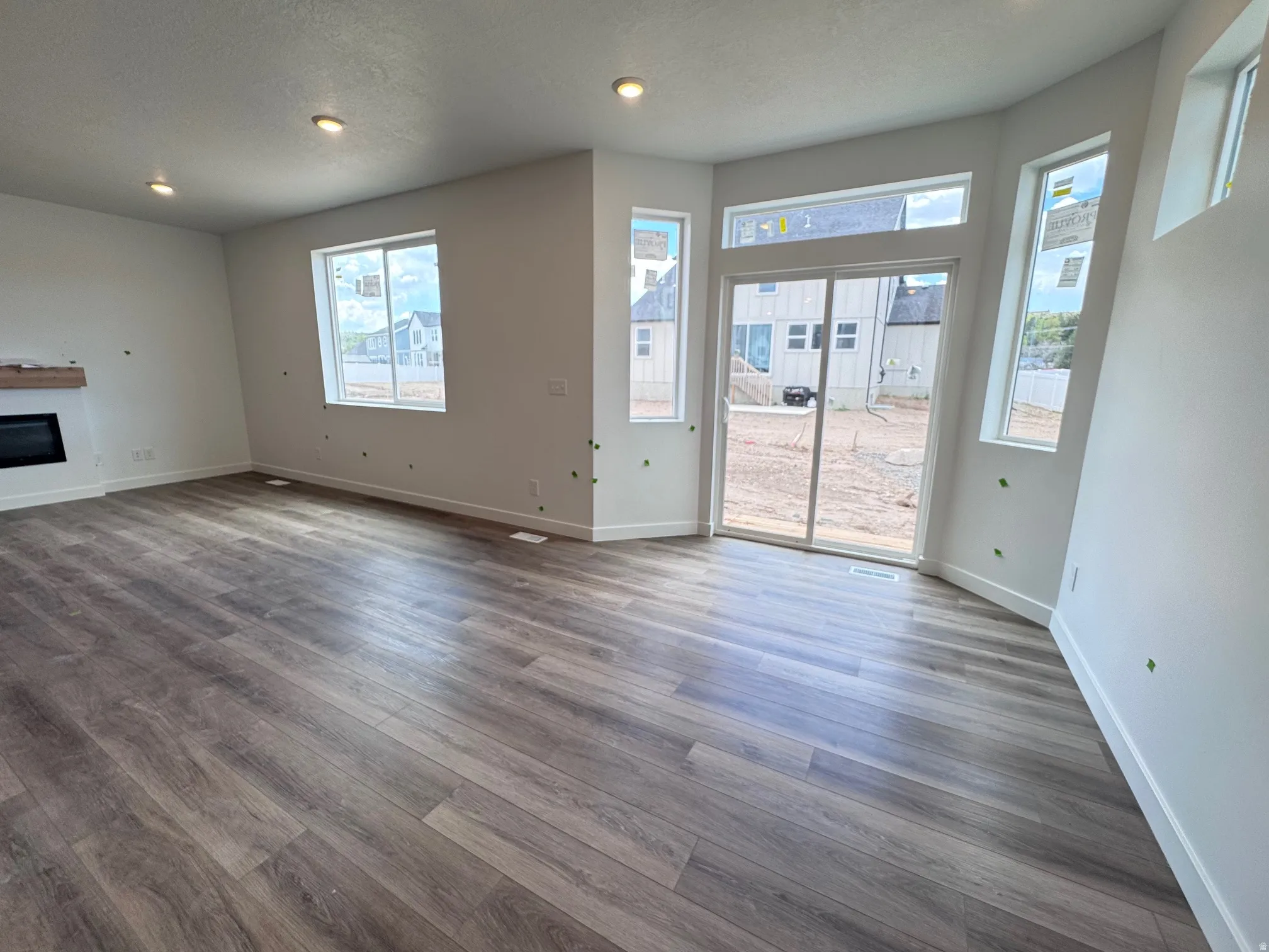 Spacious room featuring wood-finish flooring, a contemporary electric fireplace with a wood mantle, and recessed ceiling lighting