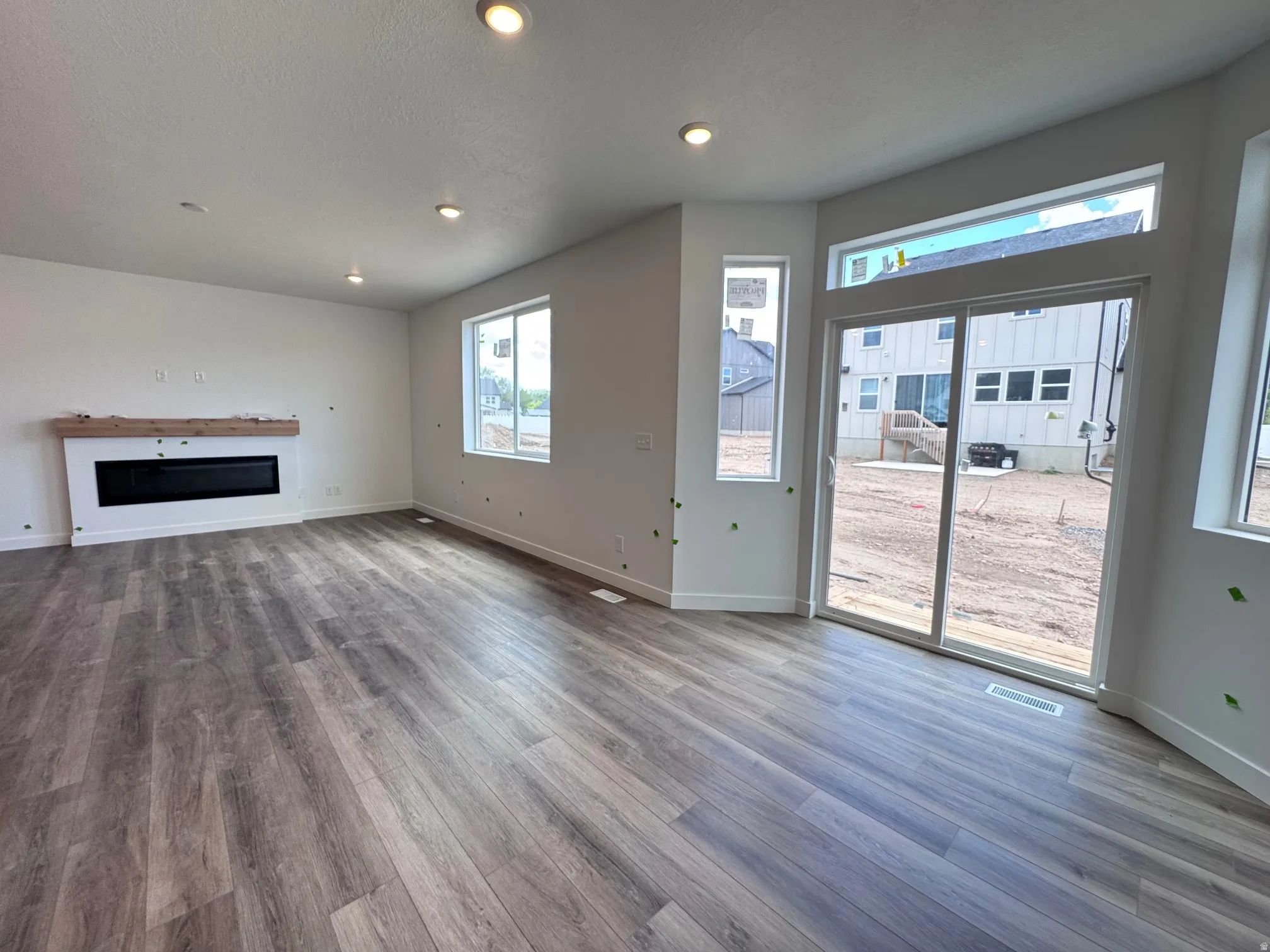 Expansive interior with wood-finish flooring, recessed lighting, and a modern linear fireplace featuring a wood mantle