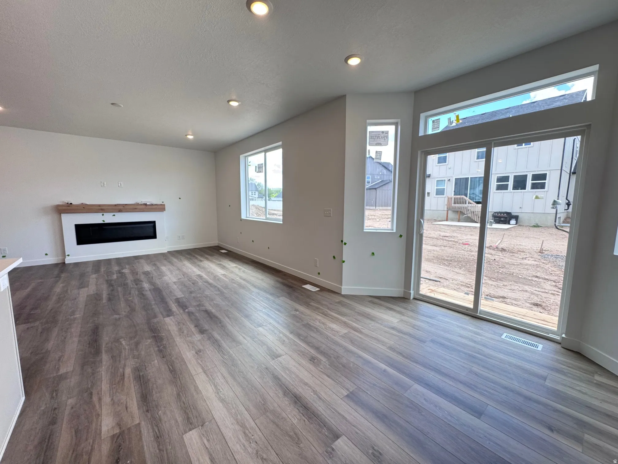 Spacious living area featuring wood-finish flooring, recessed lighting, and a modern built-in fireplace with a light-toned wood mantel