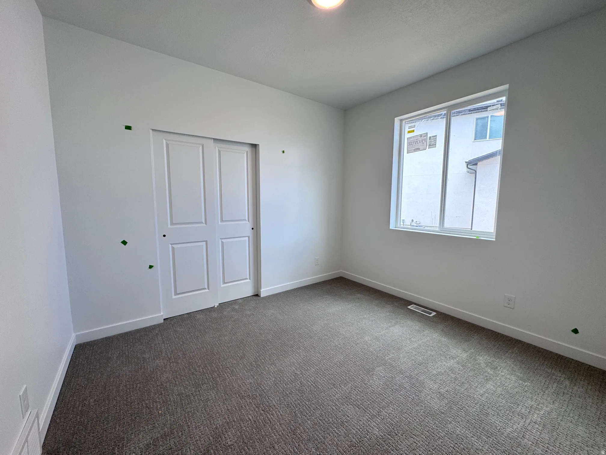 Light-filled room featuring neutral-toned carpeting, white walls, and a large window