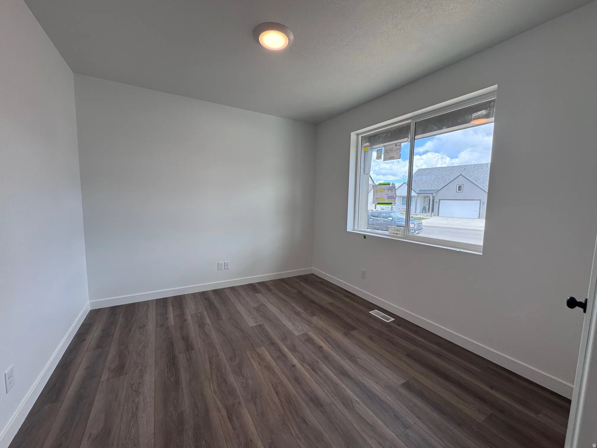 Bright room featuring wood-finish flooring, white baseboards, and a large window
