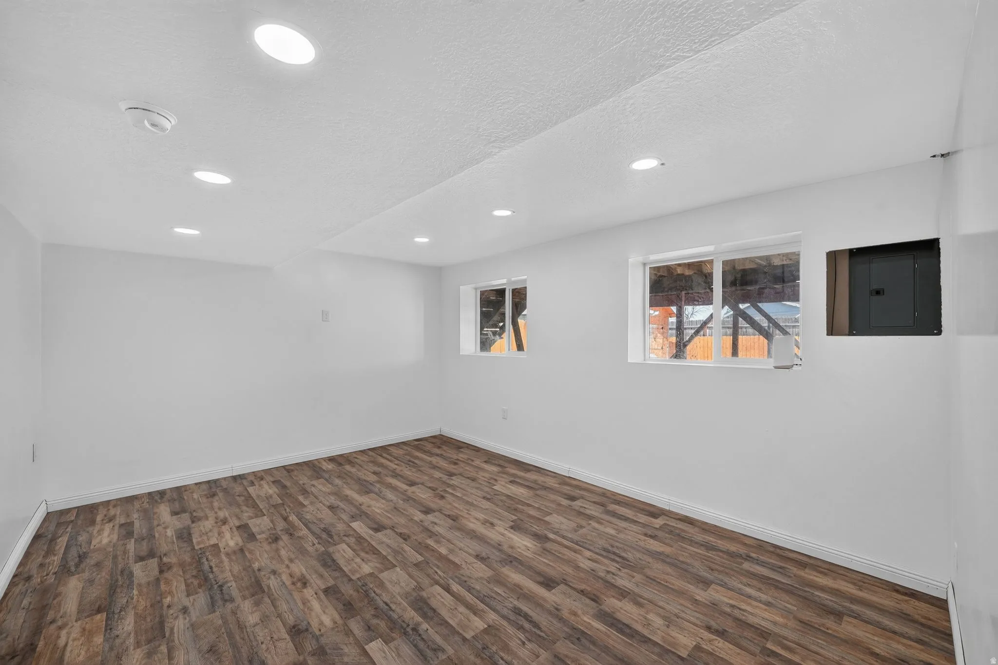 Spacious room featuring wood-finish flooring, white walls, and recessed ceiling lighting