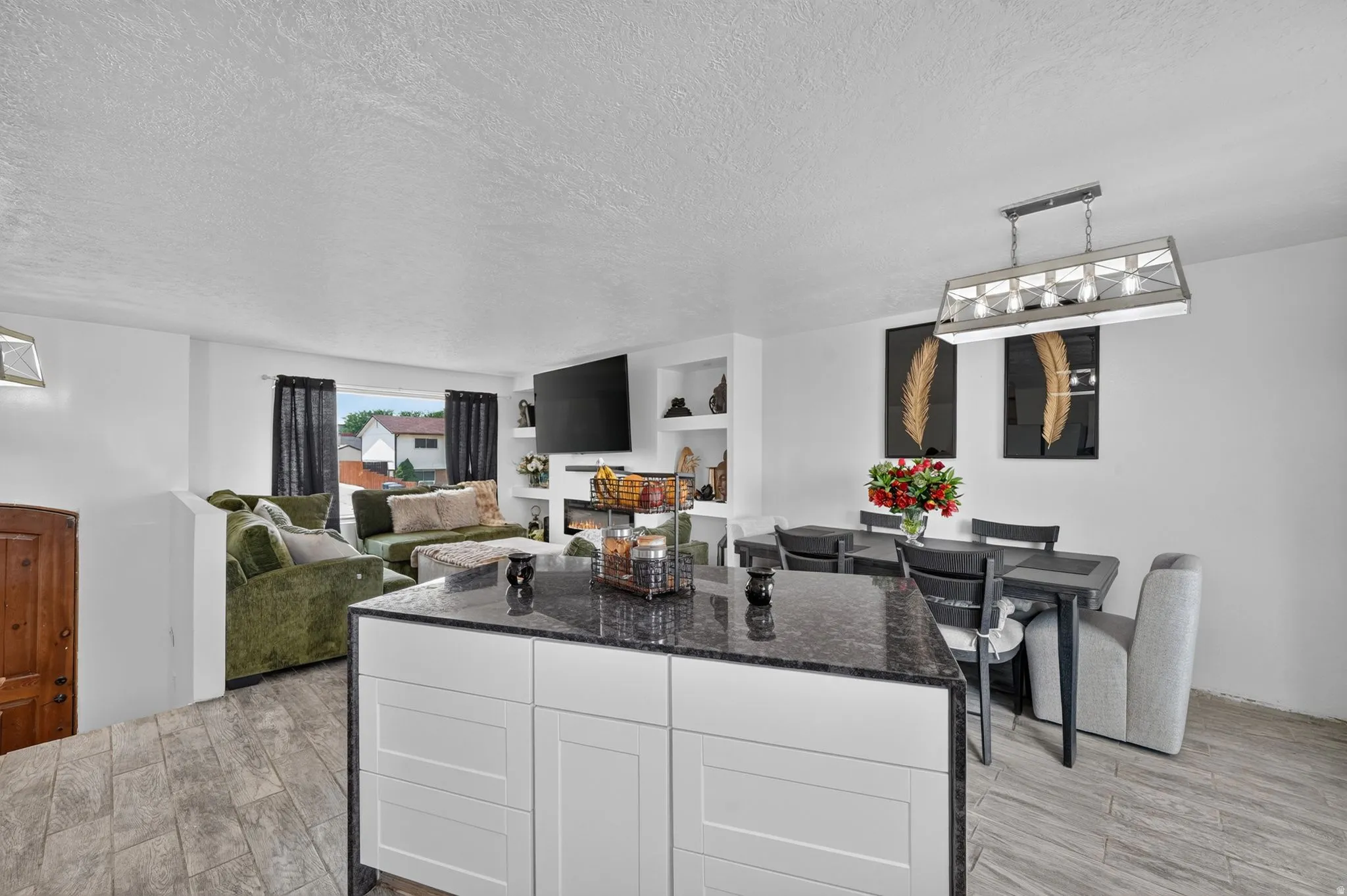 Kitchen island with dark countertop, white cabinetry, and wood-finish flooring