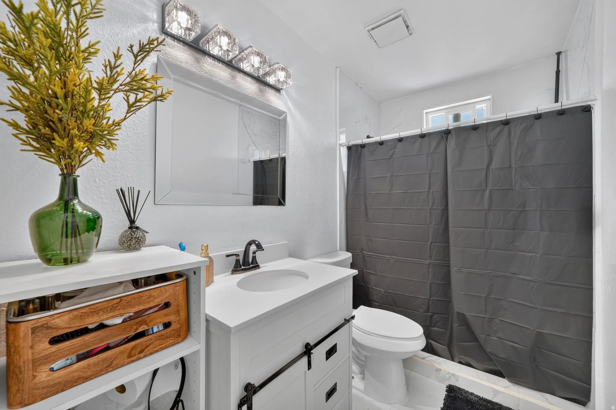 Bathroom featuring a single vanity with an integrated sink, dark bronze-finish faucet, and a contemporary vanity light fixture