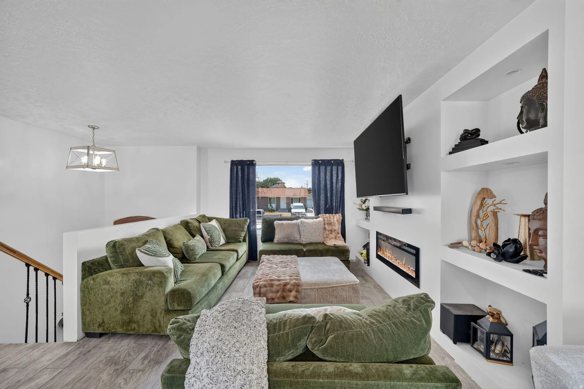 Contemporary living space featuring wood-finish flooring and a built-in electric fireplace