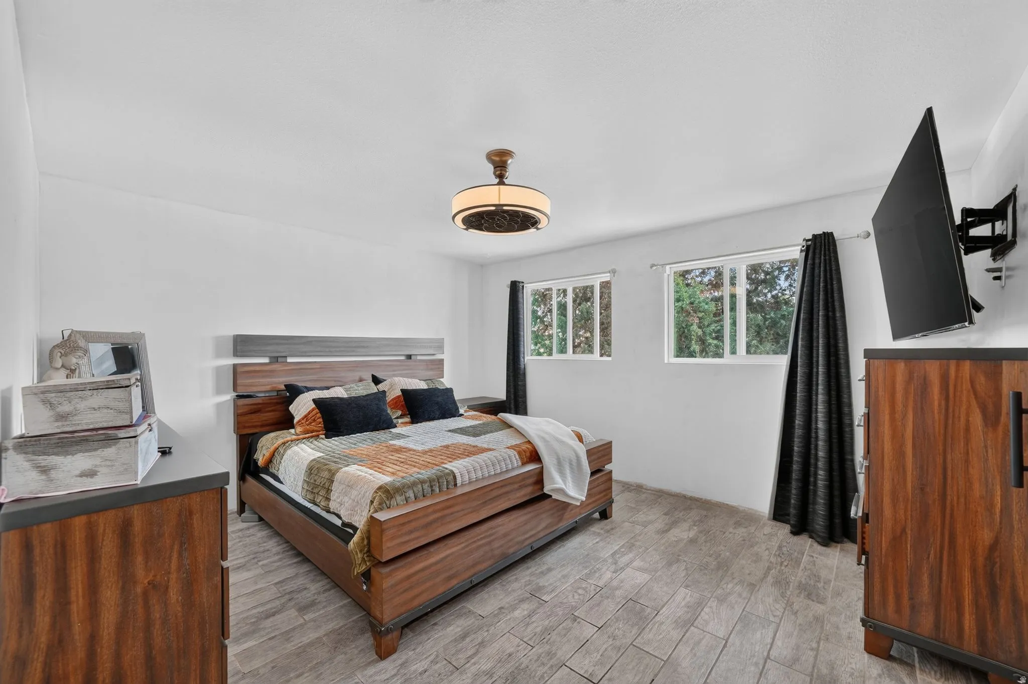 Bright room featuring wood-finish flooring, white walls, and a ceiling-mounted light fixture