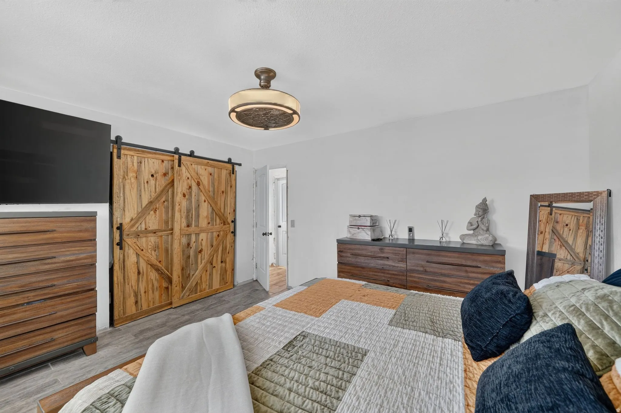 Sliding barn doors crafted from natural wood planks, gray wood-finish flooring, and an ornamental ceiling light fixture