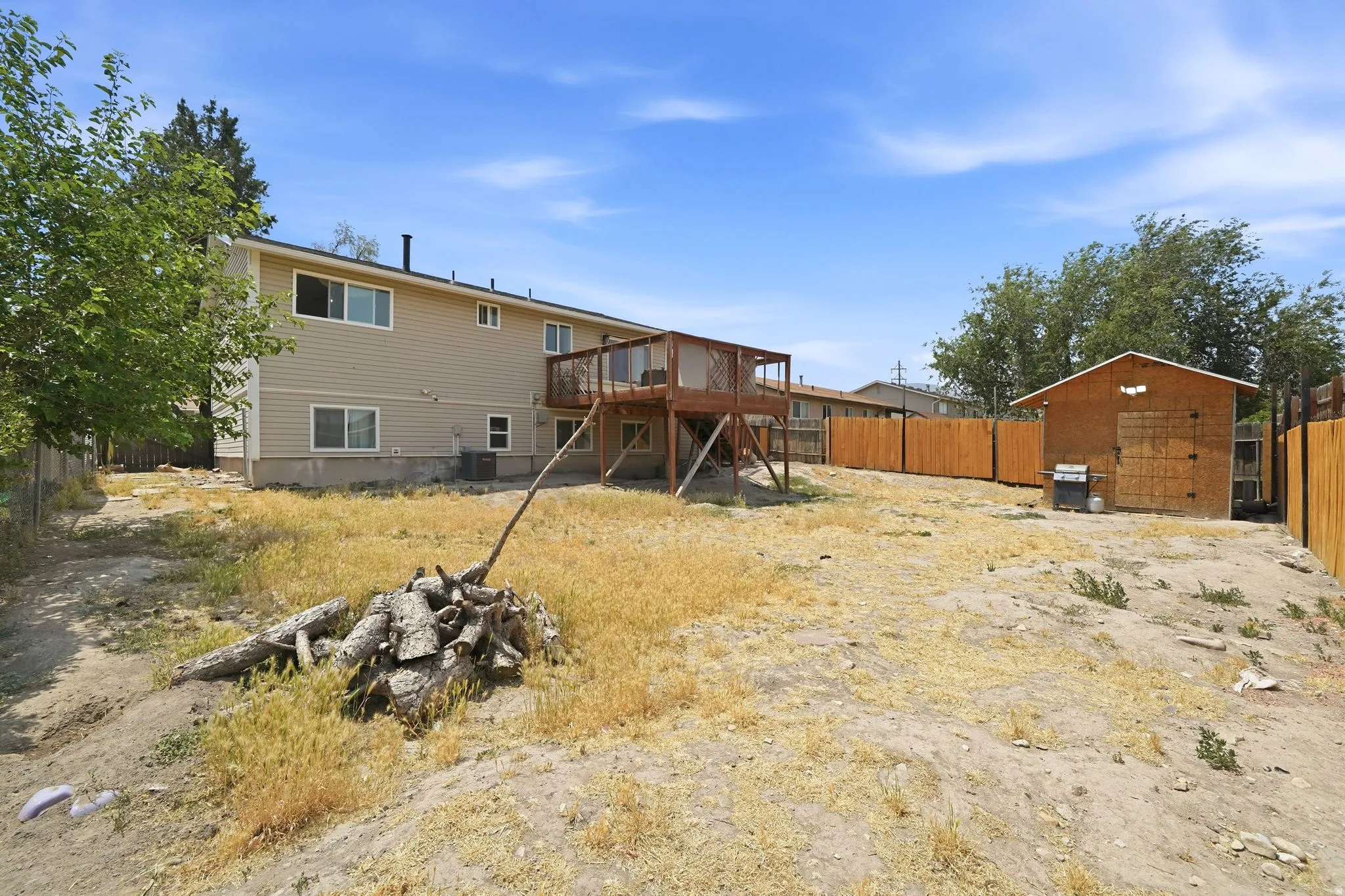 Expansive yard featuring a multi-level wood deck, wood privacy fencing, and a separate storage shed