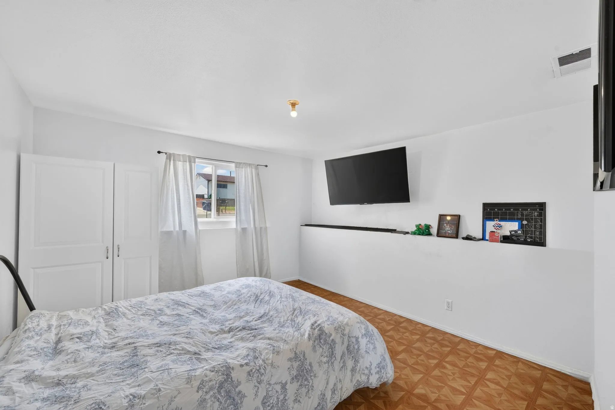 White walls with crown molding, wood-finish flooring, a single window, and built-in white cabinetry