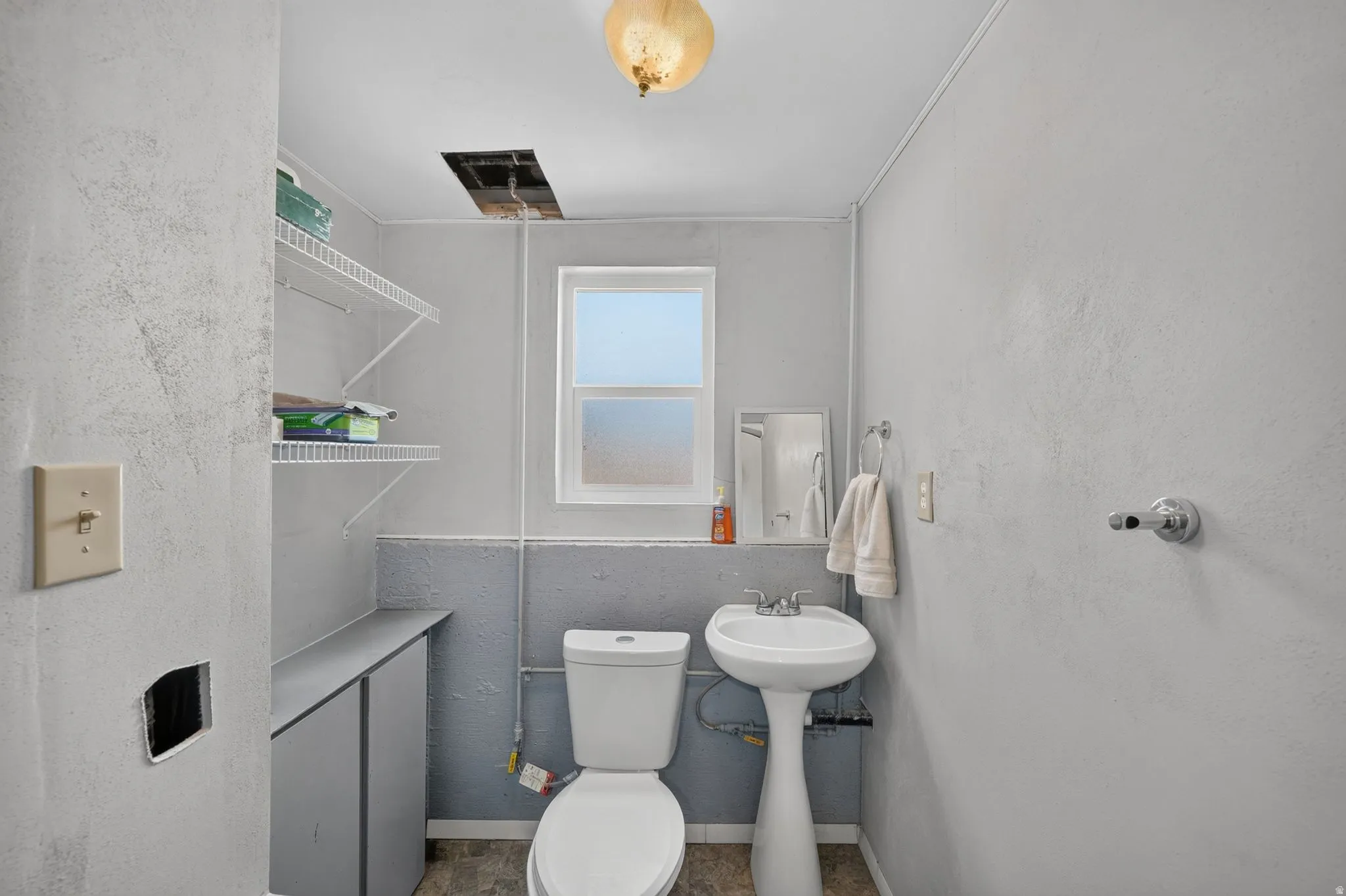 Pedestal sink with white basin, toilet, and a window with frosted lower pane