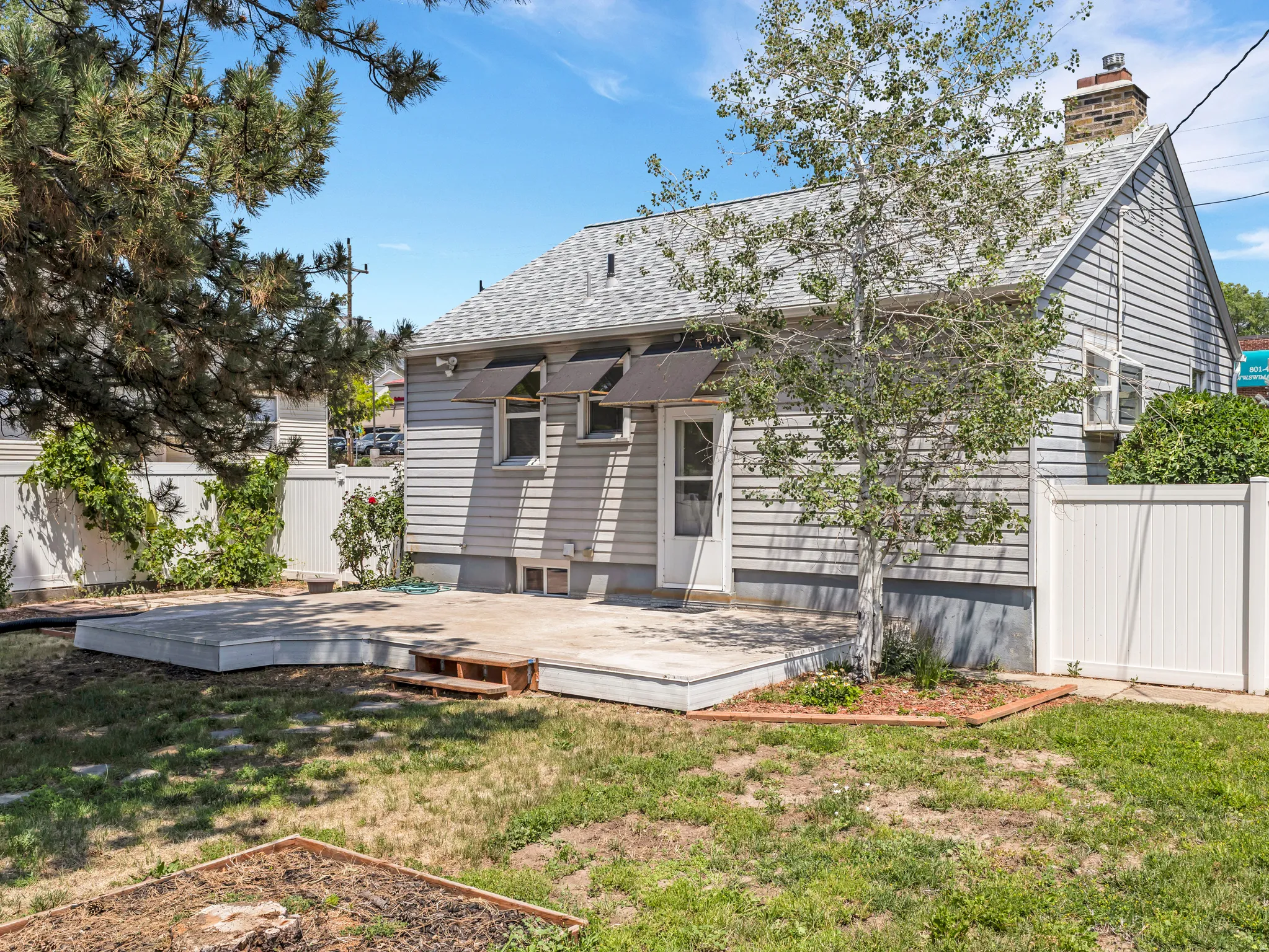 Rear exterior featuring a spacious elevated deck, light gray siding, and a white privacy fence