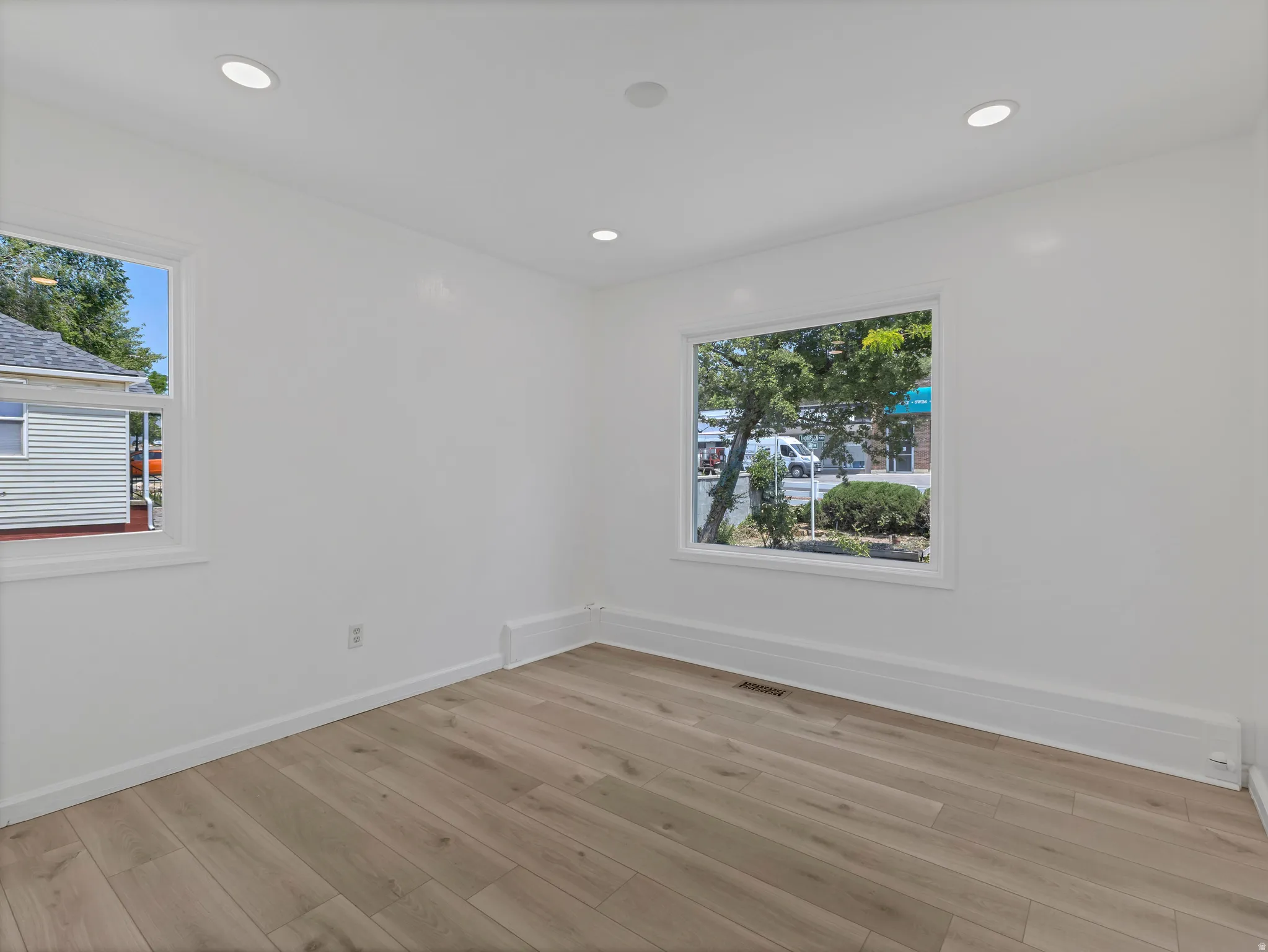 Room featuring light wood-finish flooring, recessed ceiling lighting, and white baseboards