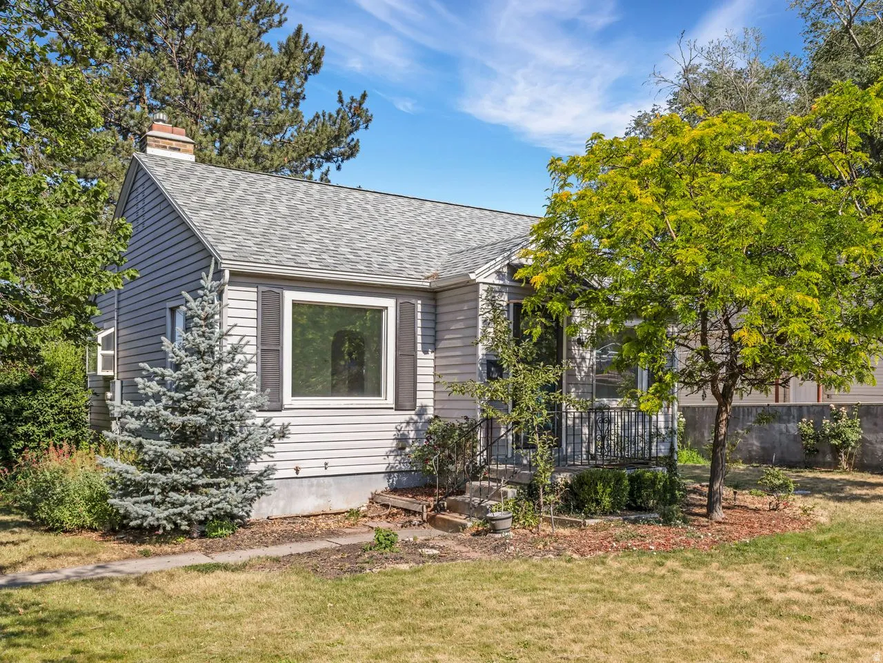Light gray siding exterior with a gabled roof and a prominent front window featuring dark shutters