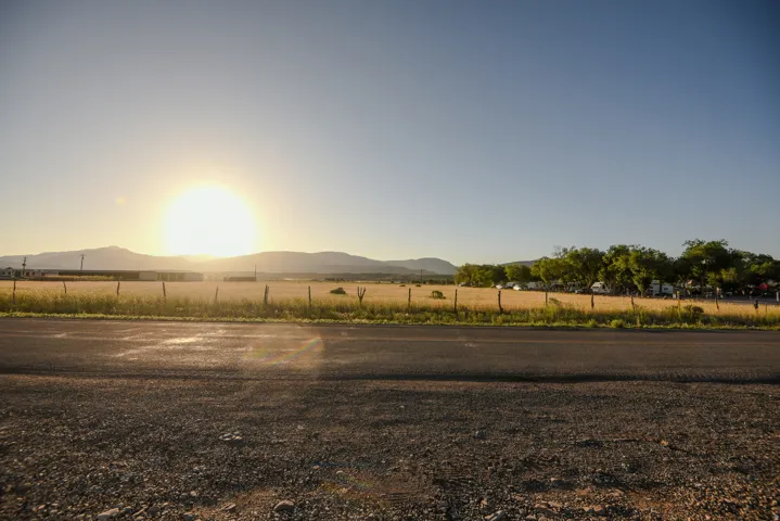 Expansive undeveloped land featuring a partial wire fence and distant trees