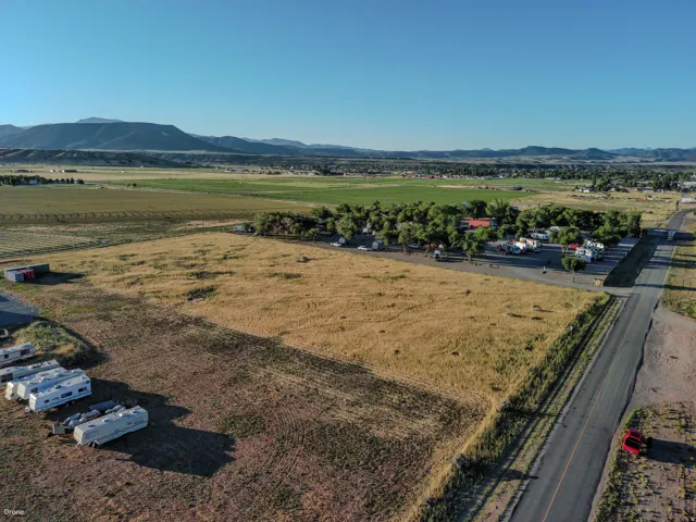 Expansive undeveloped lot featuring a paved road frontage, mountain backdrop, and clear sky