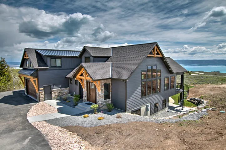 Modern Craftsman-style exterior featuring a combination of gray siding, stone accents, and natural wood structural elements