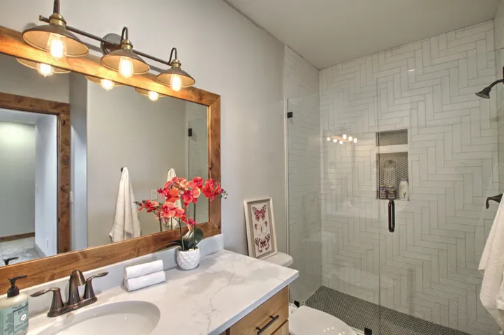 Bathroom featuring a walk-in shower with herringbone tile, glass enclosure, and built-in niche