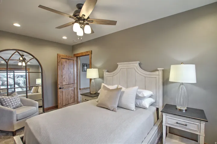 Room featuring a paneled wood headboard, wood-finish interior door with dark hardware, a ceiling fan with integrated lighting, and recessed lighting