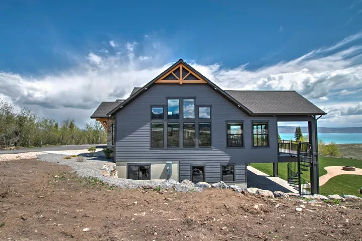 Contemporary home exterior featuring dark gray siding, a prominent gabled roofline with exposed wood trusses, and a multi-level window arrangement