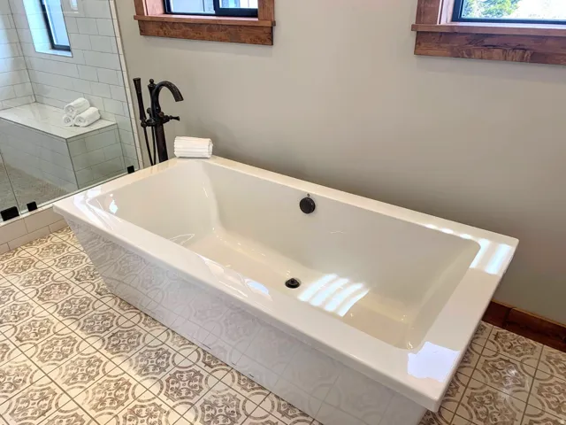 Freestanding soaking tub with a floor-mounted bronze-finish faucet