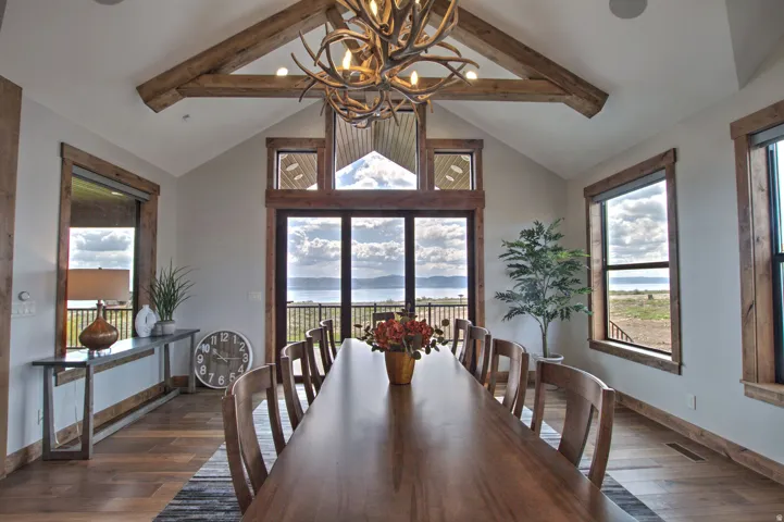 Vaulted ceiling with exposed wood beams, large sliding glass doors, and panoramic water scenery