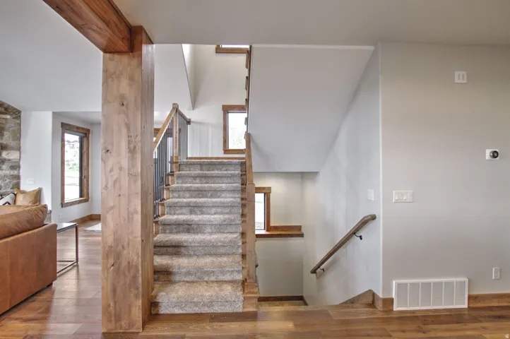 Staircase with wood-finish treads and risers, carpet runner, and metal balusters