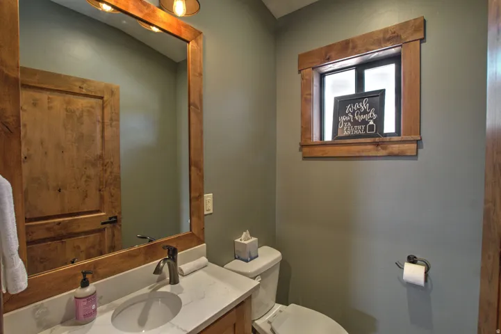 Bathroom featuring a wood-framed mirror, wood-finish vanity, and a white countertop with an undermount sink