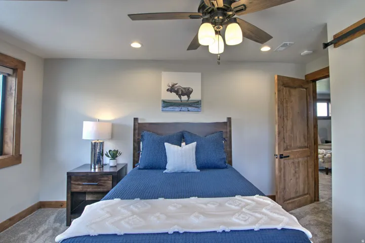 Bedroom featuring wood-finish door and trim, recessed lighting, and a ceiling fan with integrated lighting