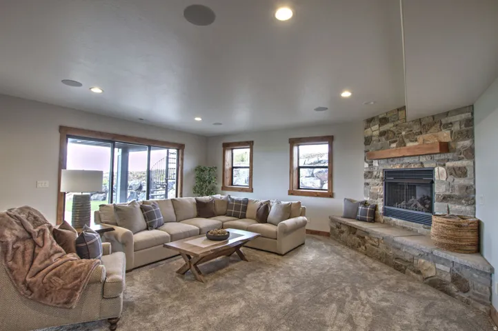 Living area featuring a stone-clad fireplace with a wood mantel, a built-in stone bench, and recessed lighting