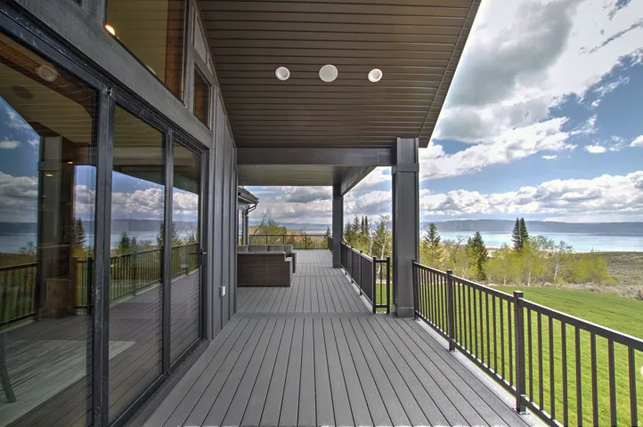 Expansive covered deck featuring composite decking, metal railings, and recessed lighting