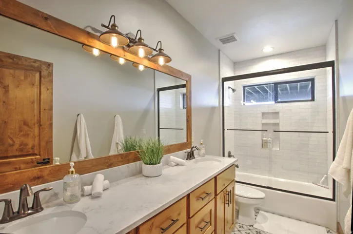 Double vanity with stone-finish countertop, wood-finish cabinetry, and bronze-finish fixtures