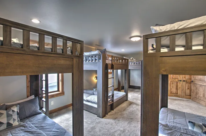 Room featuring multiple built-in wood bunk beds with ladders