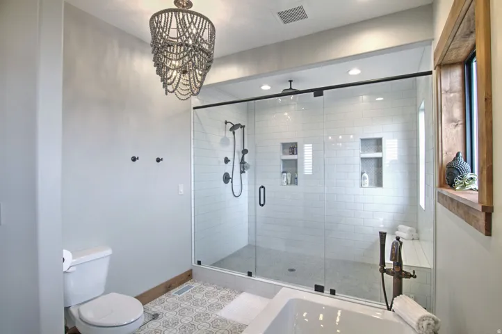 Spacious bathroom featuring a glass-enclosed shower with subway tile, built-in niches, and a rainfall showerhead