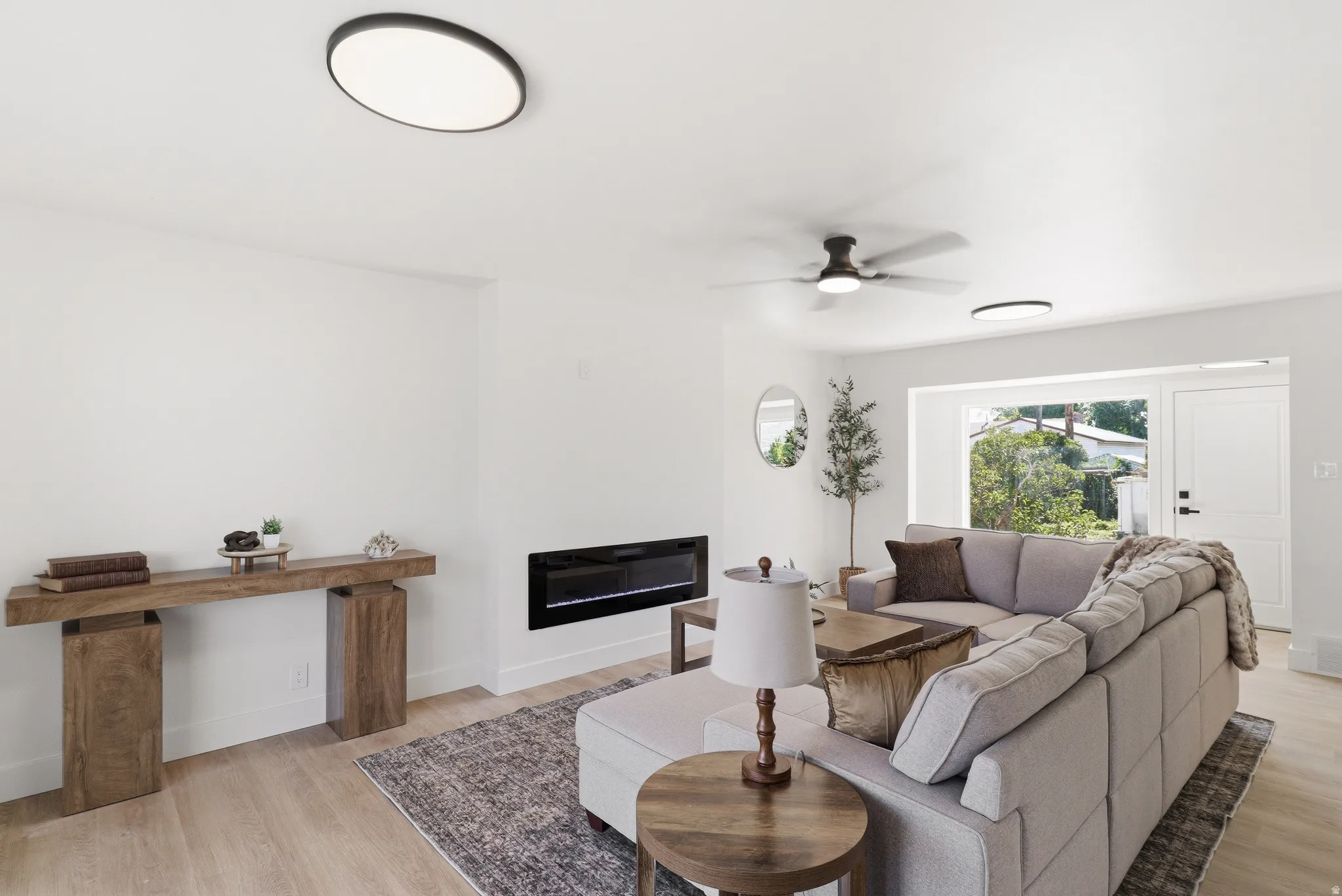 Bright living space featuring a linear electric fireplace and wood-finish flooring
