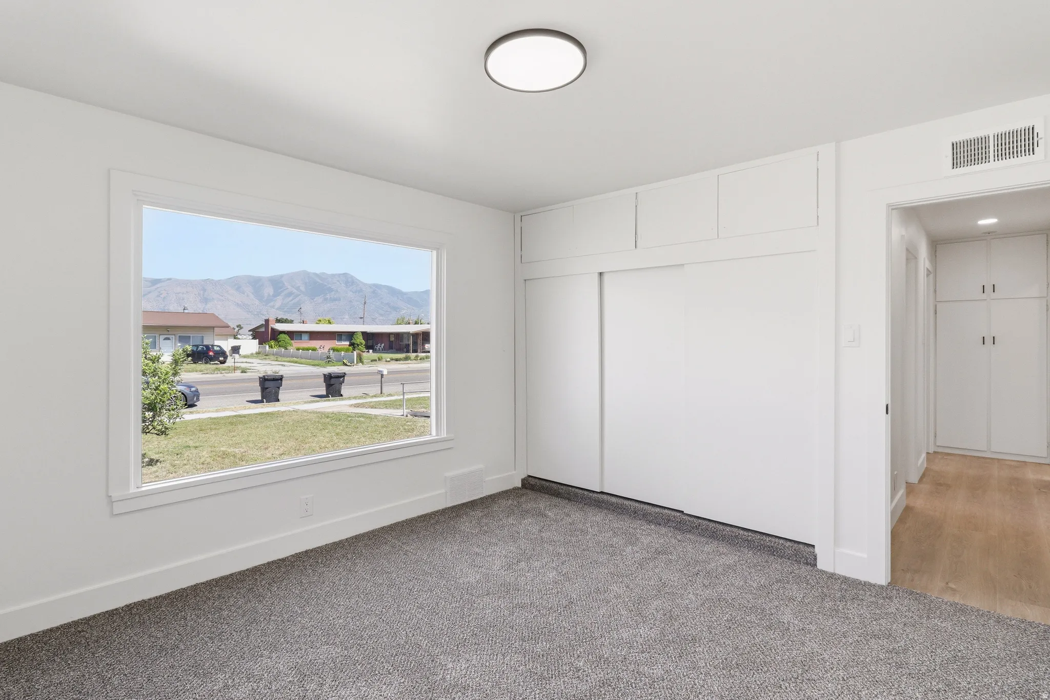 Bedroom featuring a mountain backdrop, wall-to-wall carpeting, white baseboards, a built-in closet with sliding doors and upper cabinetry, and a flush-mount ceiling light