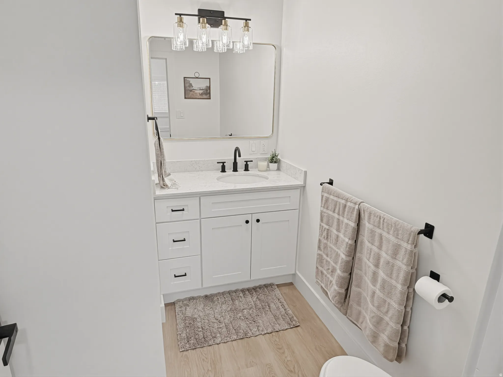 Vanity with white shaker cabinetry, an integrated sink, and a speckled countertop
