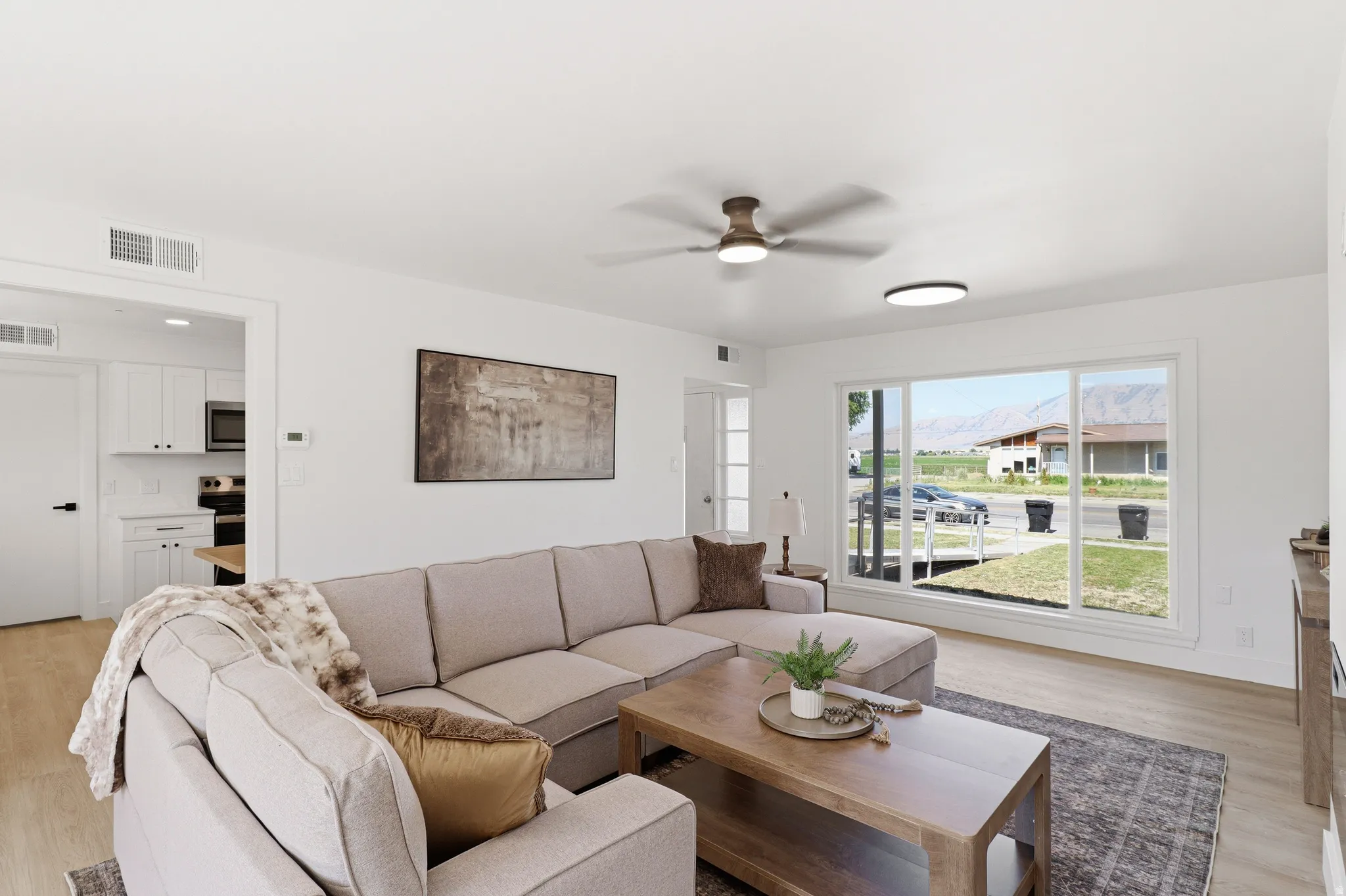 Open-concept living area featuring light wood-finish flooring and crisp white walls