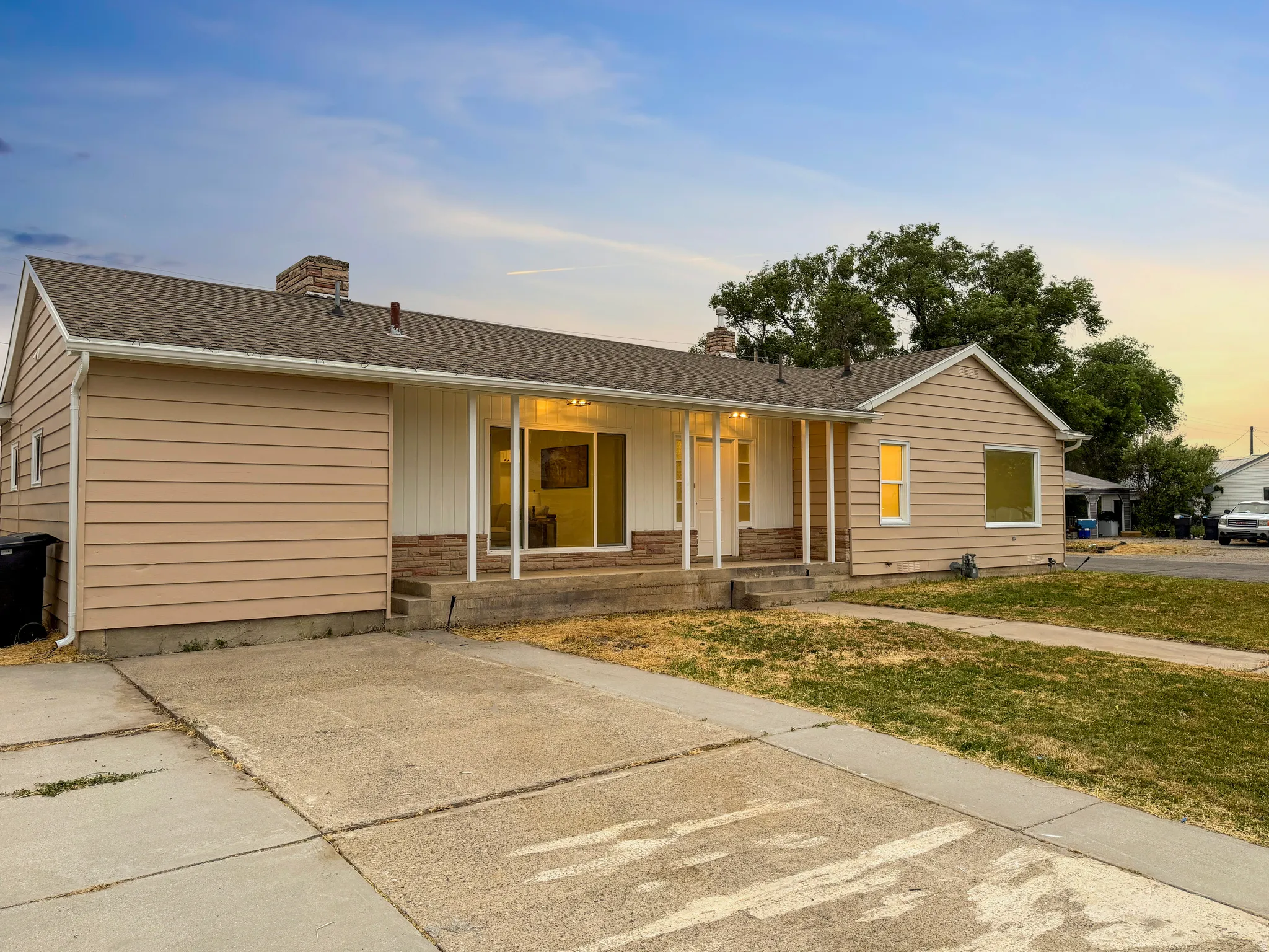 Ranch-style residence featuring horizontal siding, a covered front porch with white pillars, and a stone facade detail