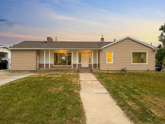 Ranch-style residence featuring a tan siding exterior, brick accents, and a covered front porch