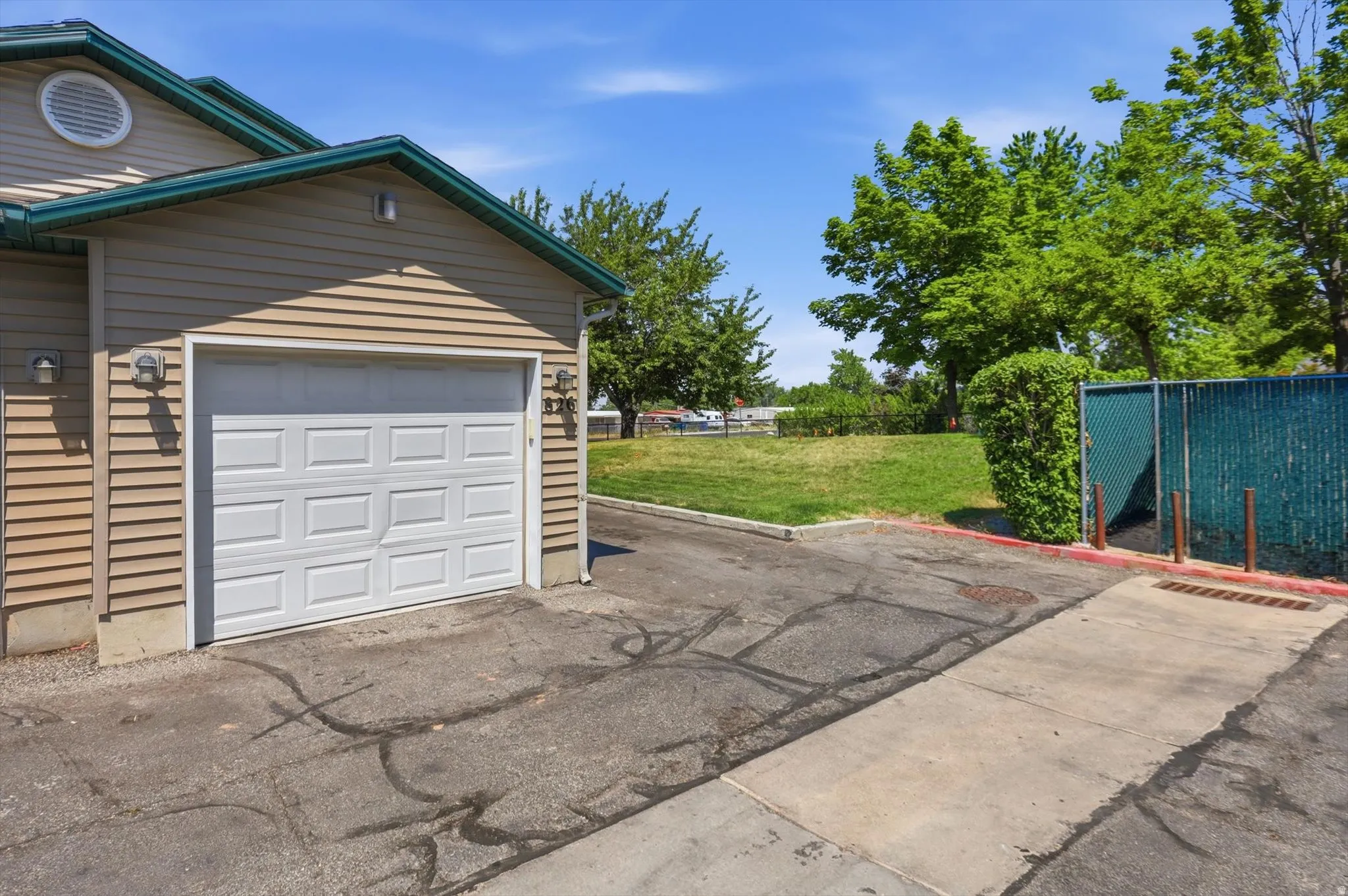 Attached single-car garage featuring a white panel door and tan horizontal siding