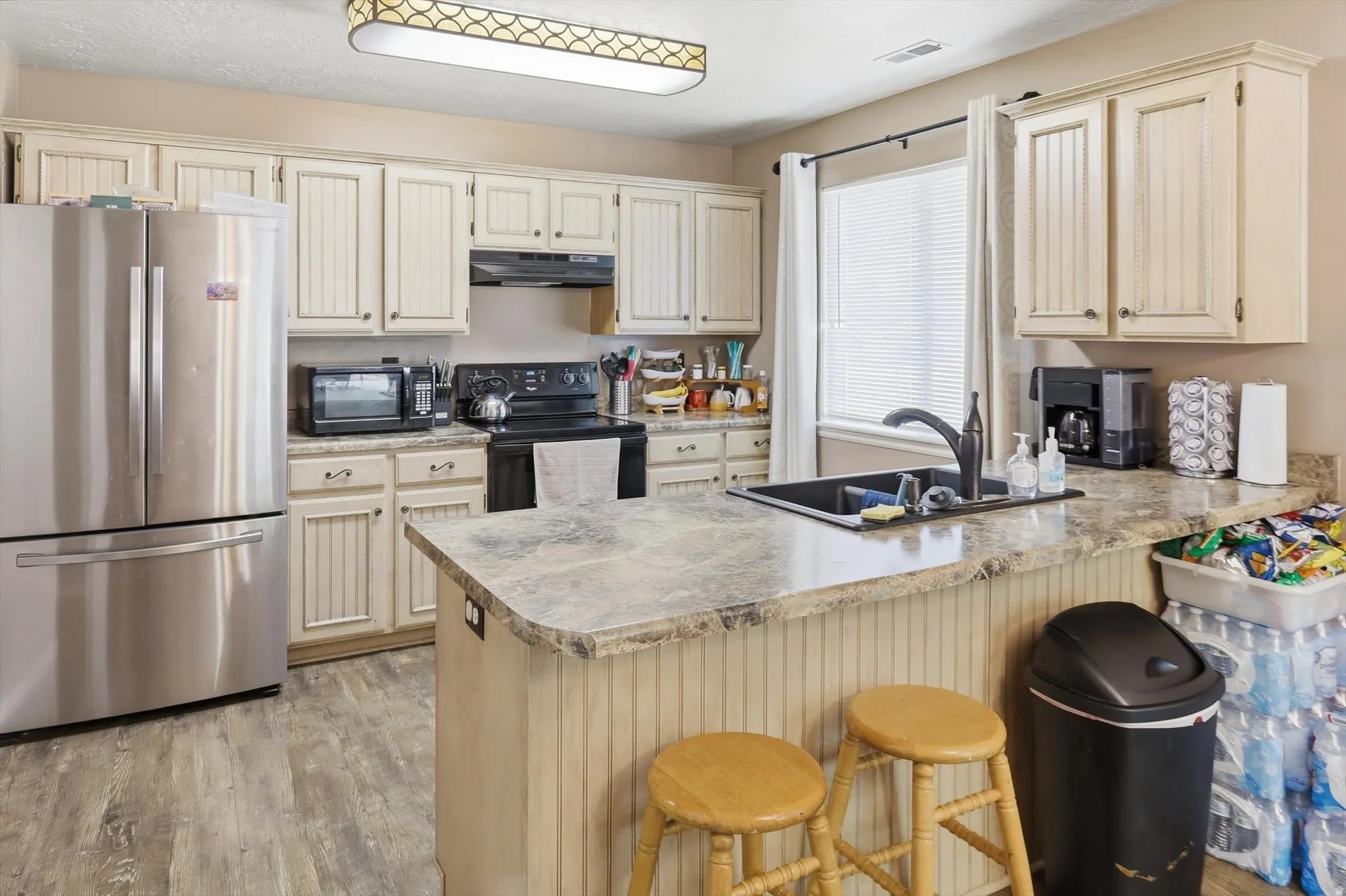 Kitchen featuring wood-finish flooring, cream-colored cabinetry, and a central island with a breakfast bar
