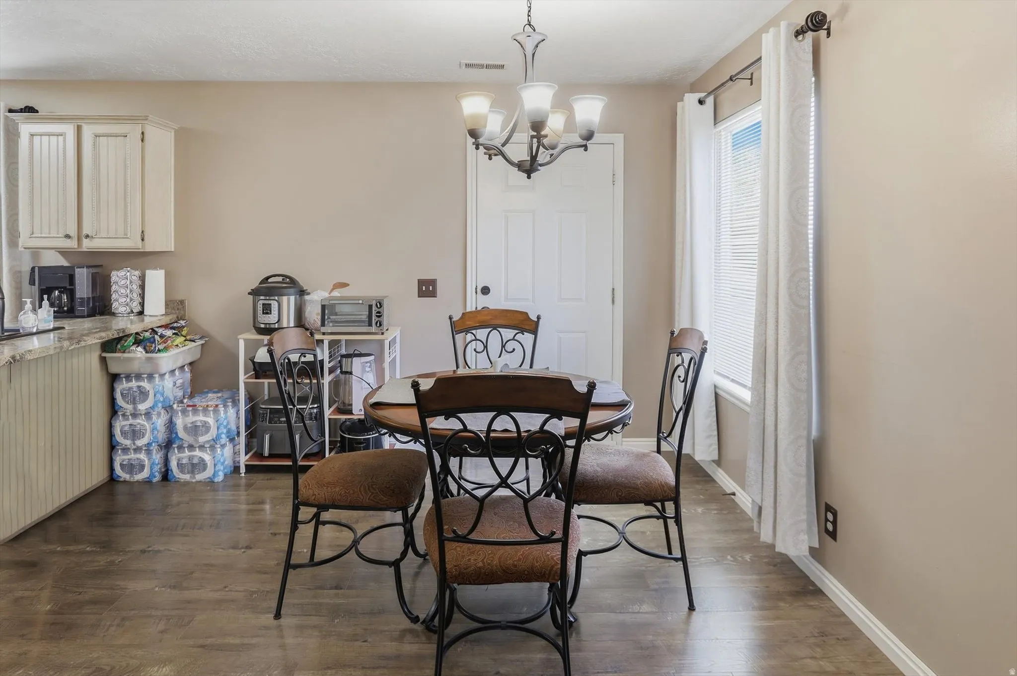 Dining area featuring wood-finish flooring, a white window with blinds and curtains, and a white paneled door