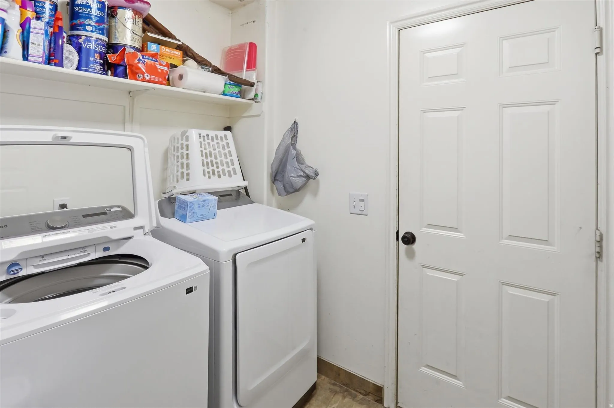 Dedicated laundry area featuring white appliances, a white six-panel interior door, and overhead shelving for storage