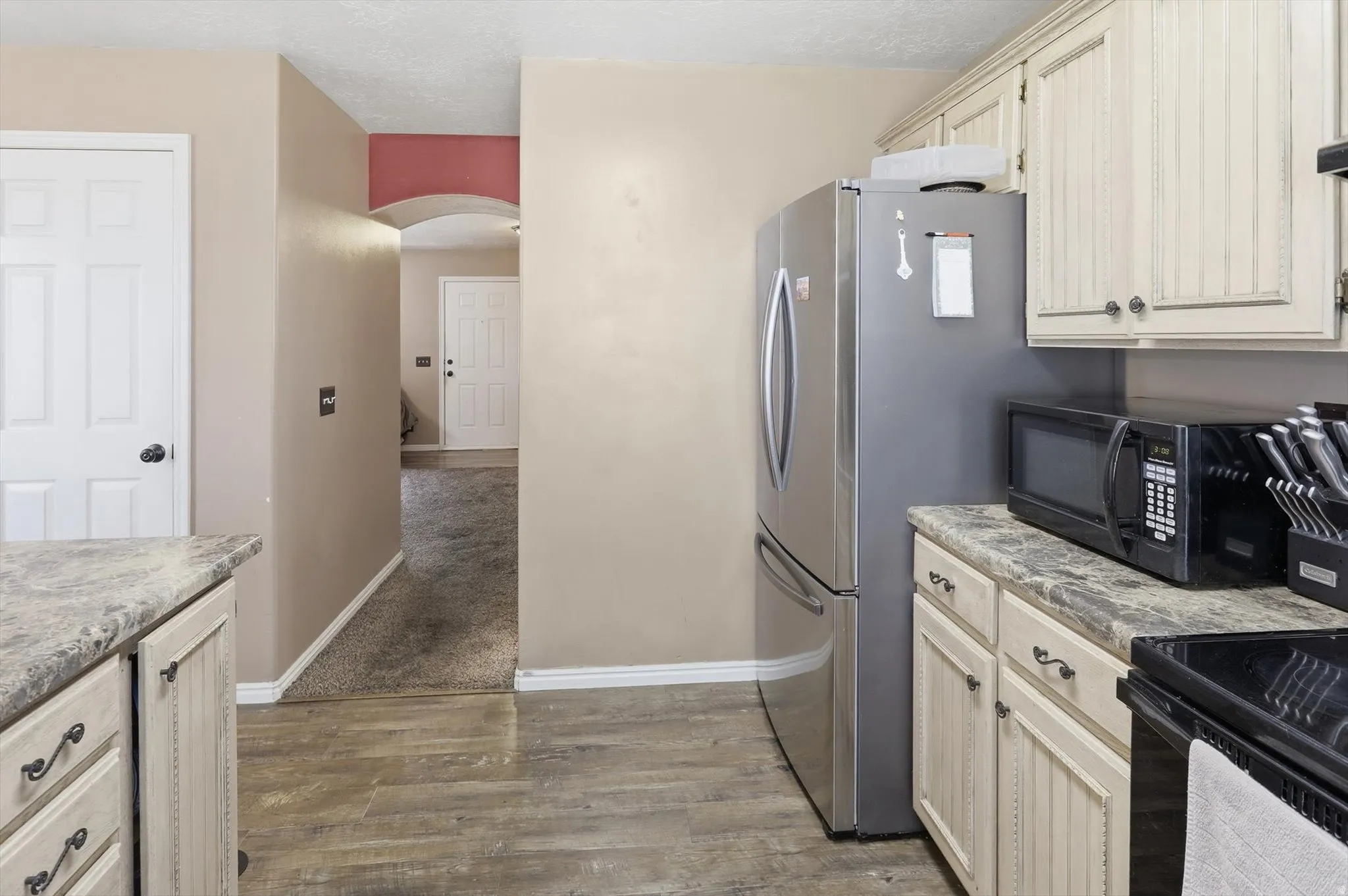 Kitchen featuring wood-finish flooring, light-toned cabinetry, and dark countertop surfaces