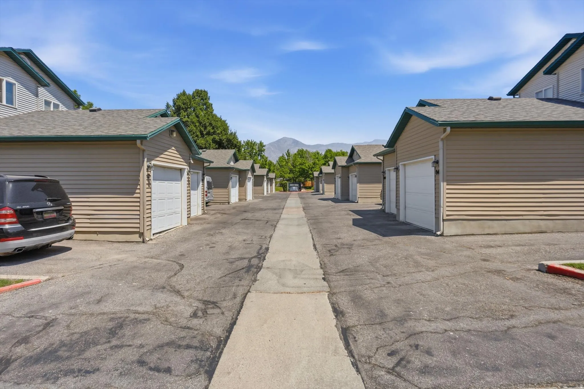 Individual garages with tan horizontal siding, white overhead doors, and dark shingle roofs