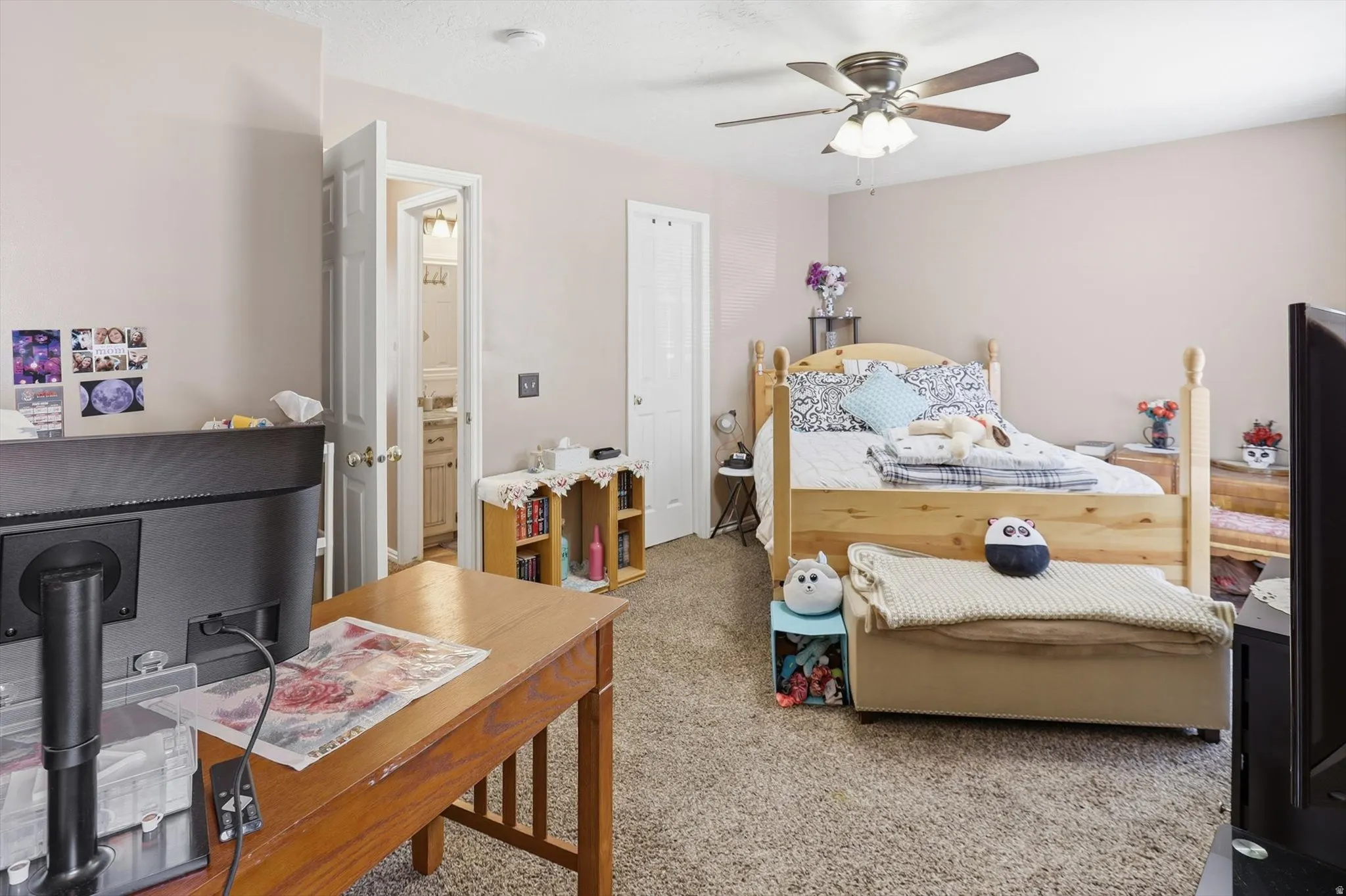 Carpeted room featuring a ceiling fan, light-toned walls, and a wooden bed frame