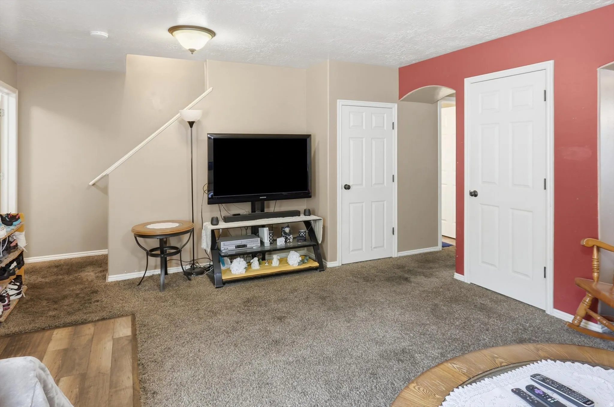 Carpeted living area featuring a neutral wall color, a red accent wall, and white six-panel interior doors