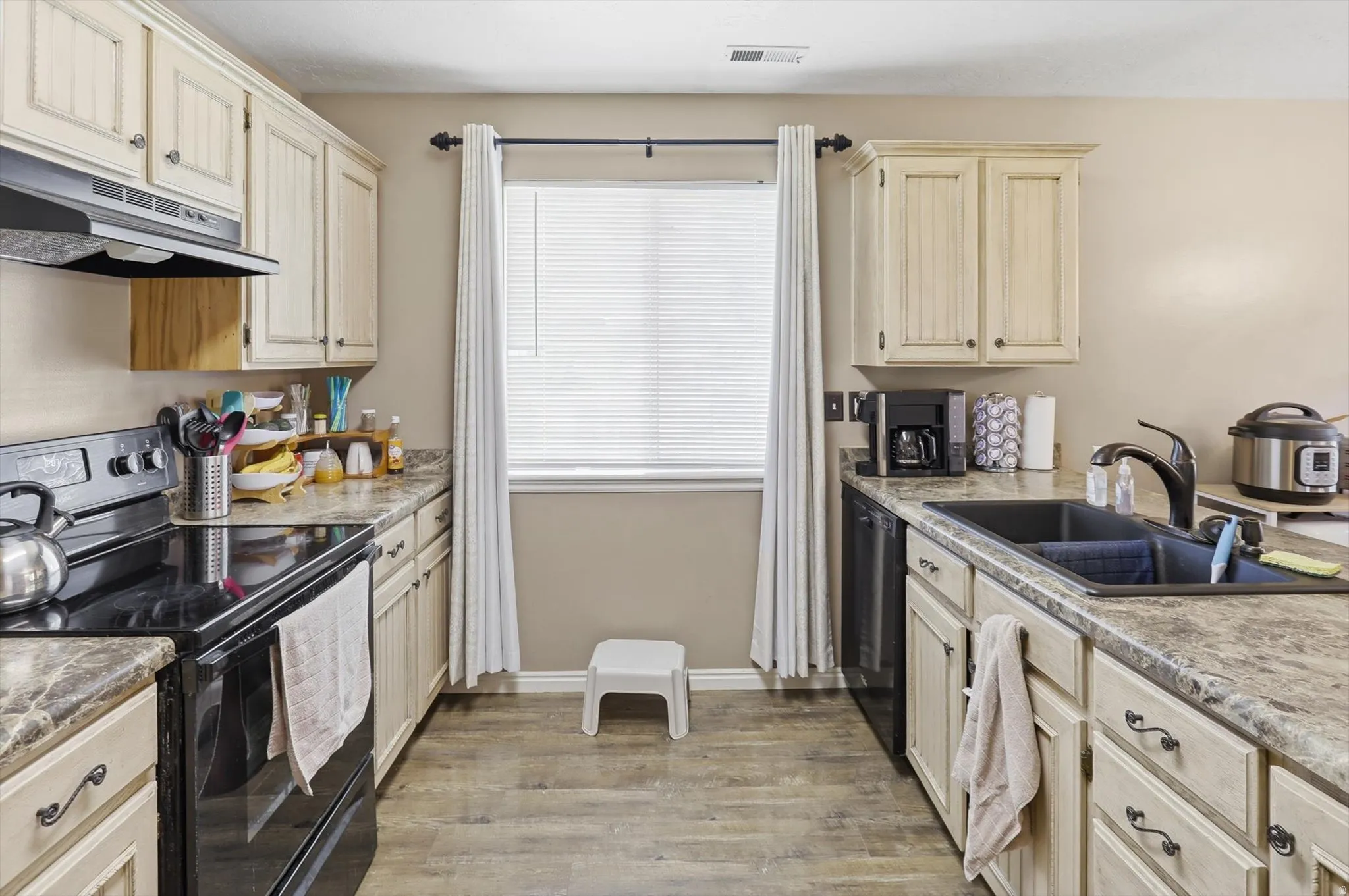 U-shaped kitchen featuring wood-finish flooring and cream-colored cabinetry