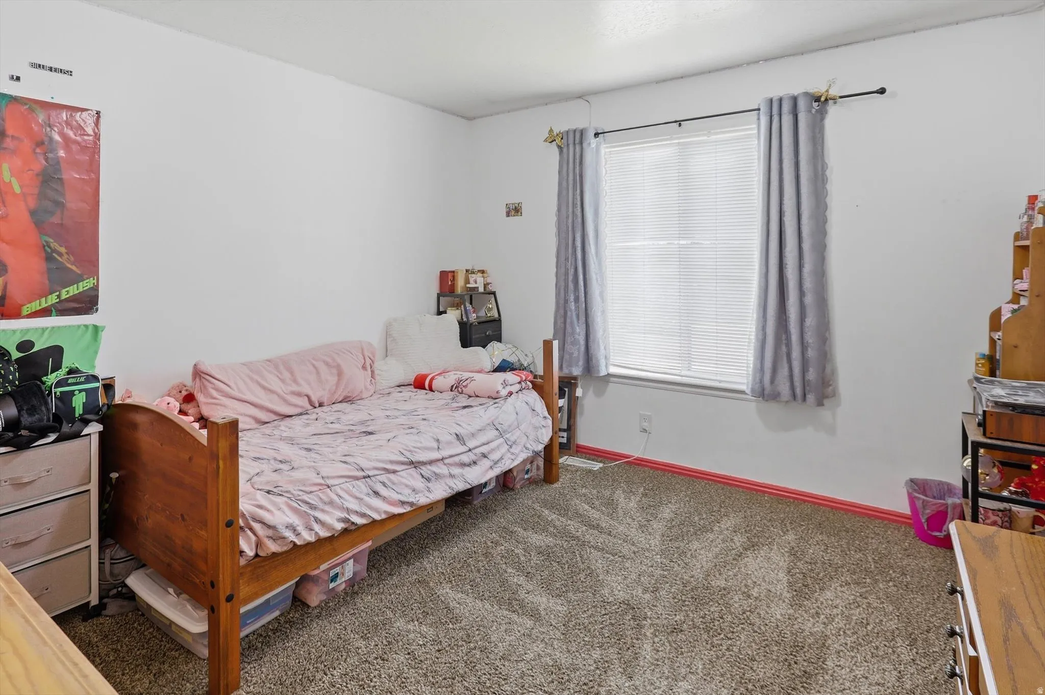 Carpeted room featuring a single window with blinds and drapes, white walls, and red baseboards